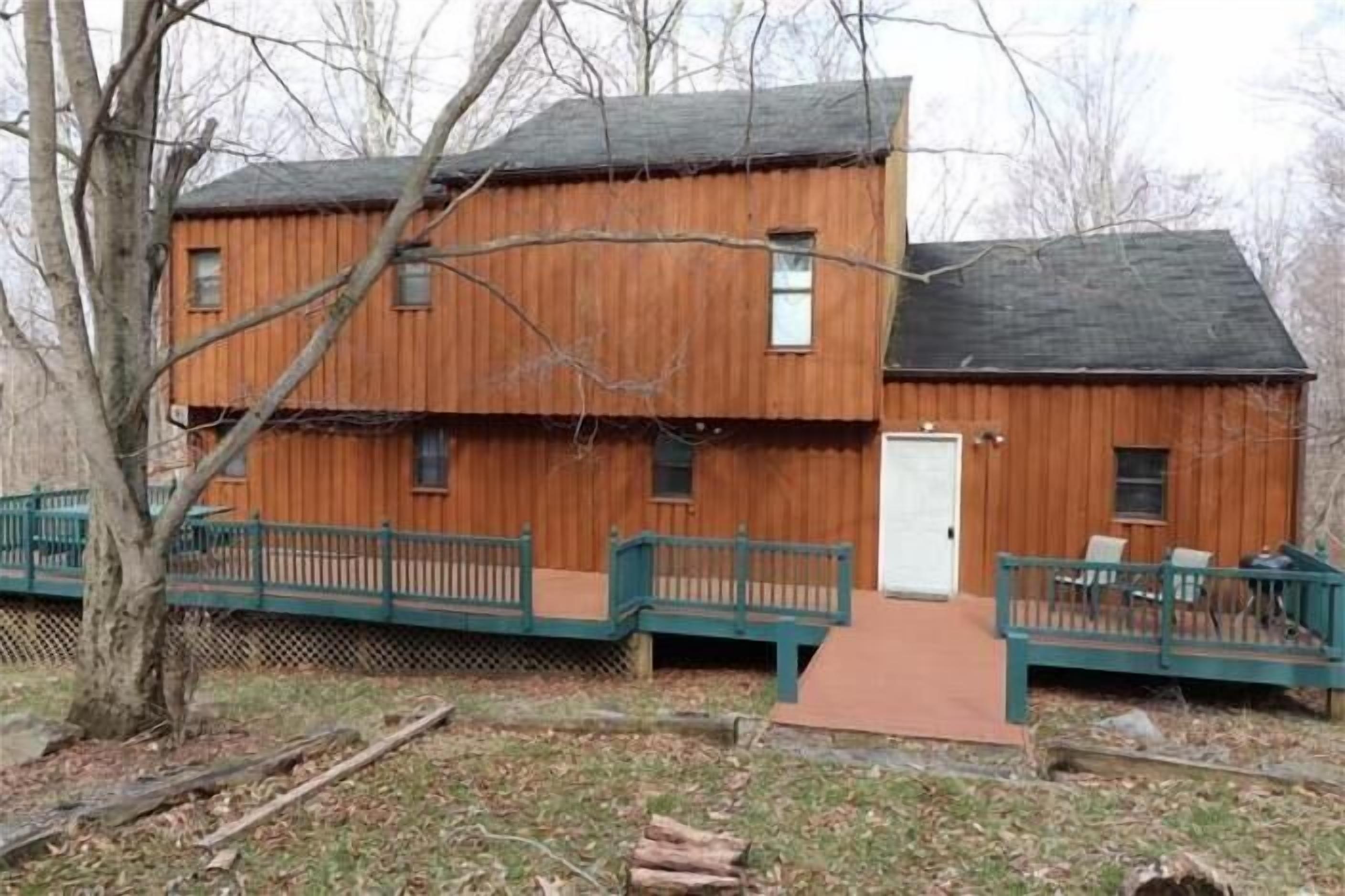 A two-story wooden cabin with a porch and a small deck.