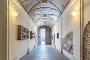 A corridor with a vaulted ceiling, a wooden cabinet, and a large stone wall. - Campo de' Fiori Amazing Terrace (Rome)