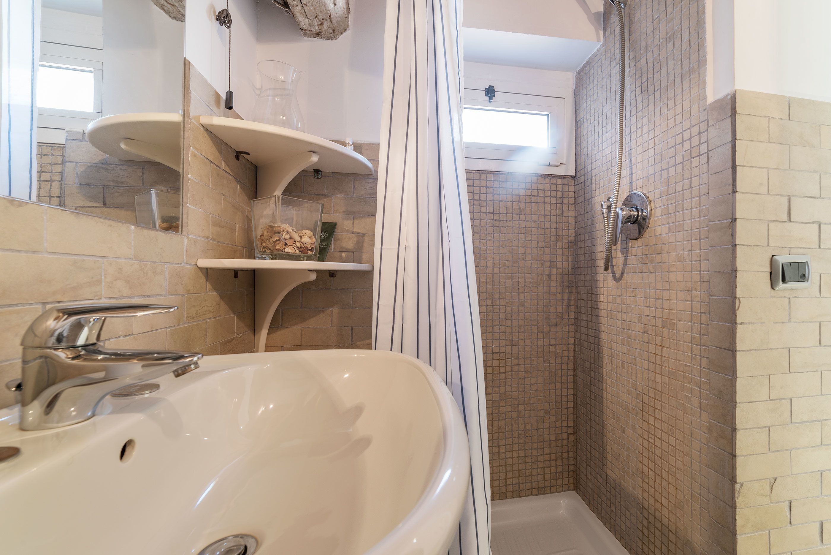 Un baño con un lavabo grande, una ducha y un muro con azulejos.