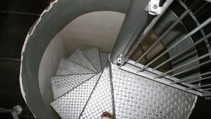 A spiral staircase with metal railings and a diamond plate floor. - Luxury Rose (Florence)
