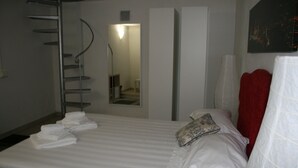 A hotel room with a neatly made bed, a mirror, and a red towel. - Luxury Rose (Florence)