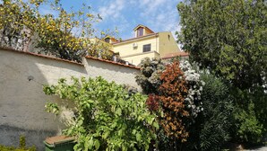 Un bâtiment jaune avec un toit rouge, entouré de différents arbres et plantes.