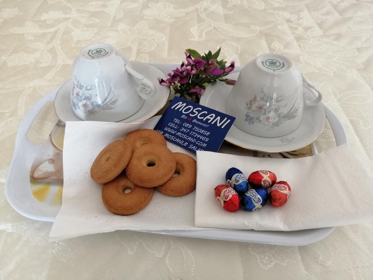 Uma bandeja com duas xícaras de chá, um cartão, biscoitos e chocolates embalados.