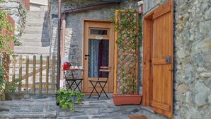 A stone building with a wooden door, a small table with chairs, and a potted plant. - Le Rosier B&B e Appartamento (Saint-Vincent)