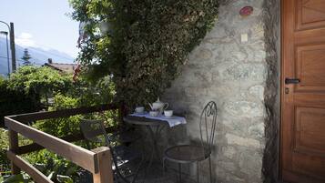 A stone wall with a wooden door, a small table with chairs, and a bench.