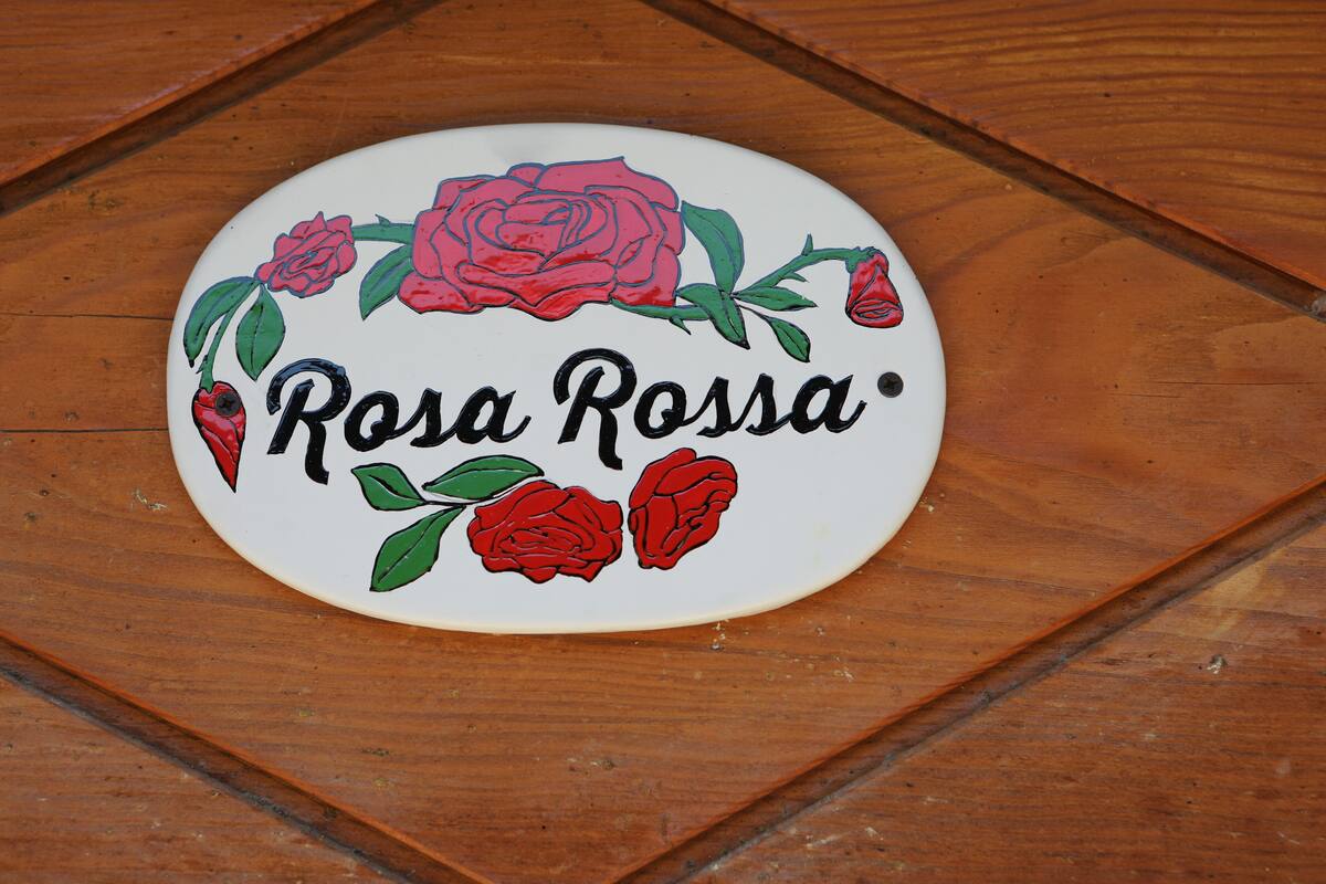 Une assiette blanche portant l’inscription « Rosa Rossa » et ornée de roses rouges.
