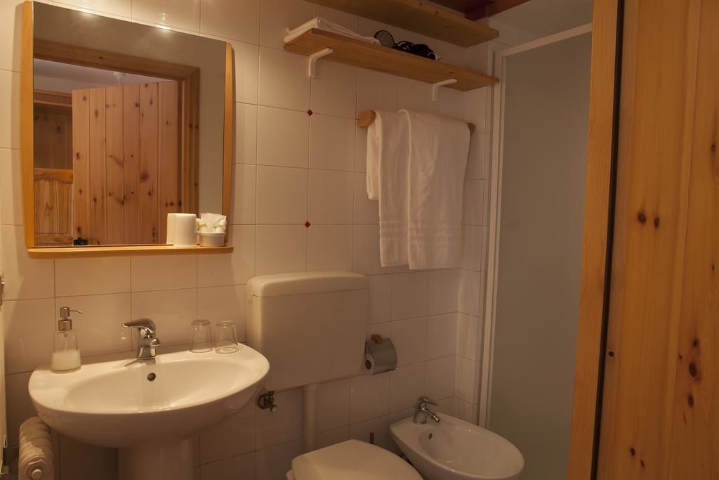 A bathroom with a sink, toilet, bidet, and a mirror.