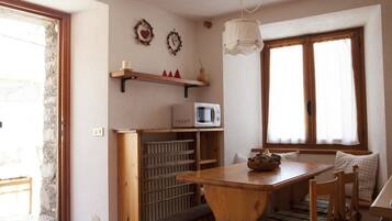 A cozy kitchen with a wooden table, a microwave, and a hanging light fixture.