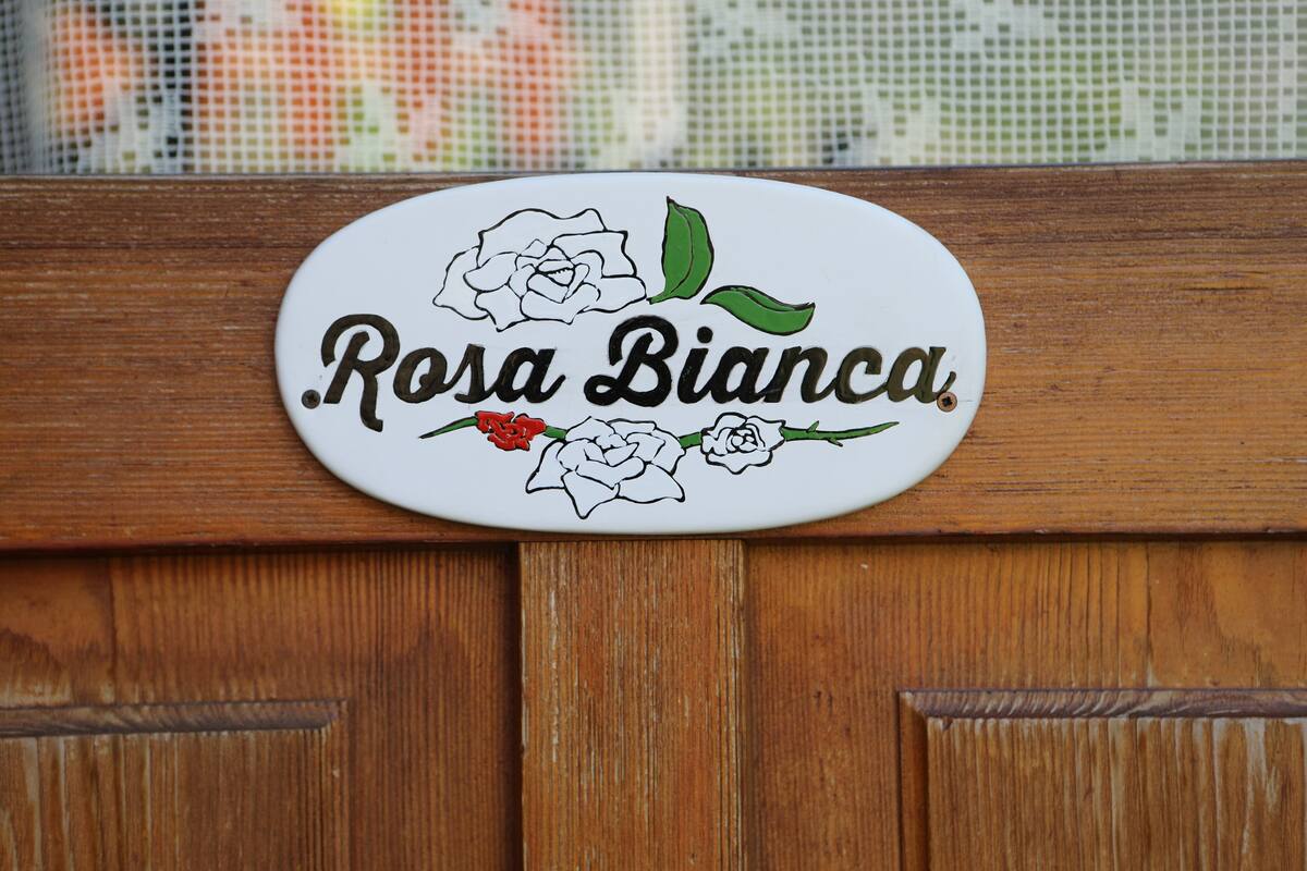 Un meuble en bois orné d’une plaque blanche portant l’inscription « Rosa Bianca » et de motifs floraux.