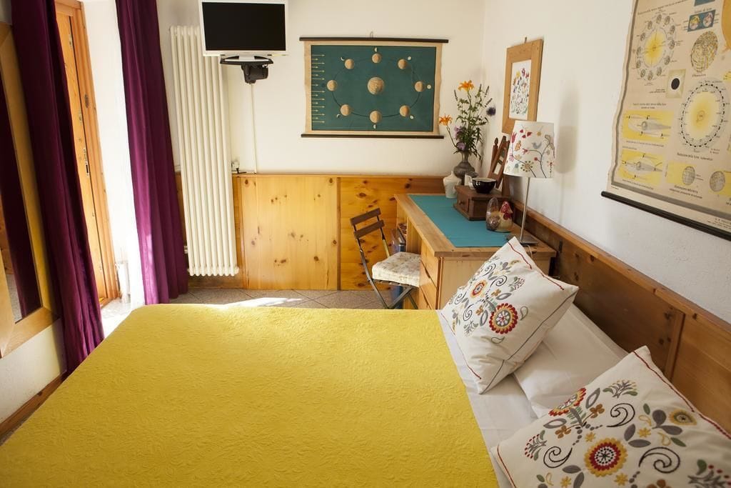A room with a bed, a desk, a chair, and a radiator.