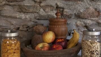 A wooden bowl filled with apples and bananas, a jar of cereal flakes, and a jar of oats.