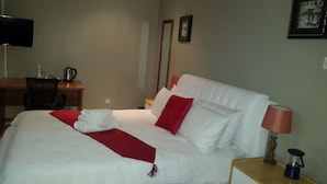 A hotel room with a bed, a desk, a chair, a television, and a lamp. - Tintech Bed & Breakfast (Francistown)
