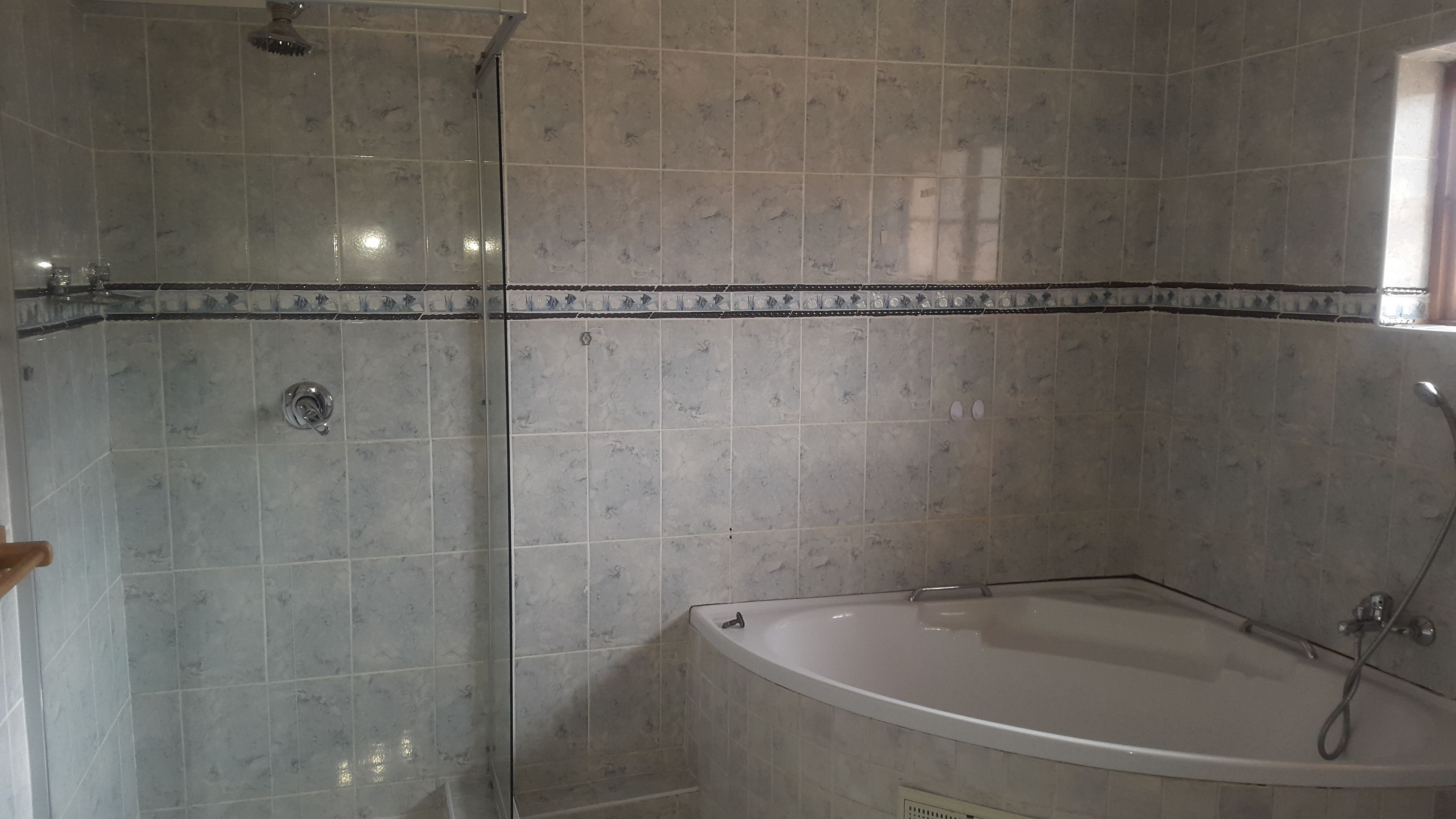 A bathroom with a shower, a bathtub, and tiled walls.