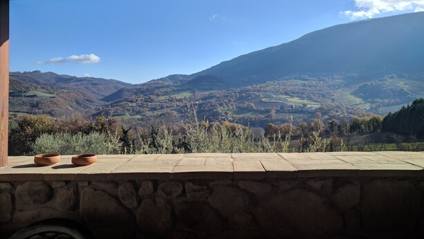 A stone wall with a view of a mountainous landscape. - Agriturismo Sole Luna (Assisi)