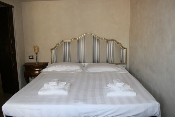 Restful retreat with a striped headboard and comfortable bed, featuring a nightstand and lamp.