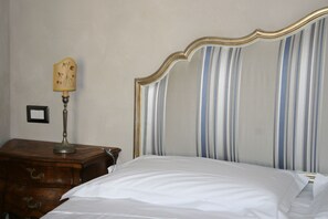 Classic design with a neatly made bed, wooden nightstand, and striped headboard.