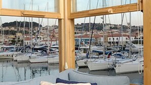 Janela de madeira com vista para uma marina e barcos.