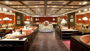 Une salle à manger d’hôtel avec de nombreuses tables, des chaises et un buffet central.