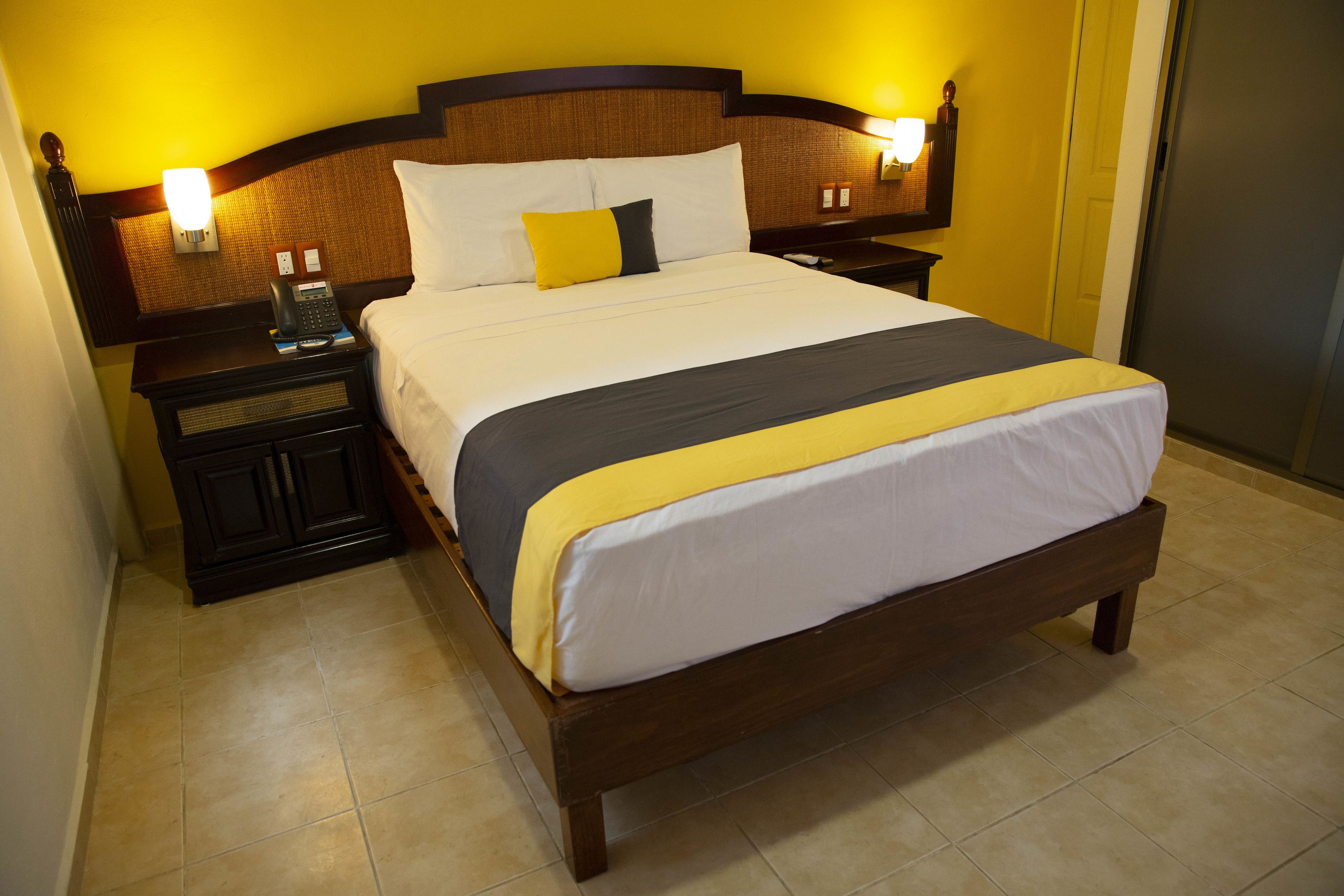 Una camera d'albergo con un letto grande, due comodini e una lampada fissata alla parete.