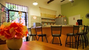 A kitchen with a dining area, featuring a wooden table, chairs, and a vase of flowers. - Casa San Juan (Mérida)