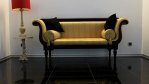 A room with a black tiled floor, a sofa with striped upholstery, and a table with a red lampshade. - Lazza Hotel (Figueira da Foz)