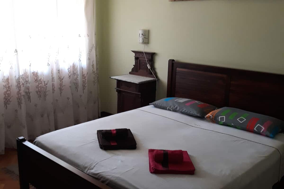 A bedroom with a bed, a nightstand, a lamp, and a painting on the wall.