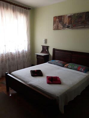 A bedroom with a bed, a nightstand, a lamp, and a painting on the wall.