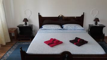 A neatly made bed with a wooden headboard, two bedside tables with lamps, and a blue patterned rug.