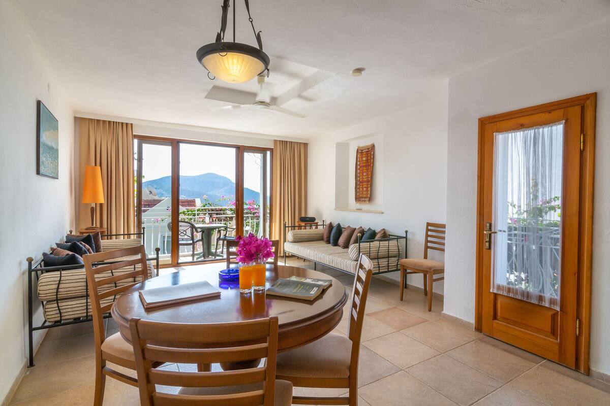 A dining area with a round table, chairs, and a view of mountains through large windows.