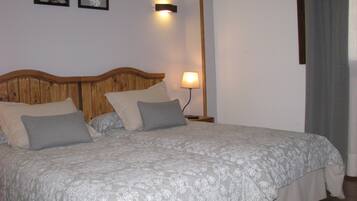 A neatly made bed with a patterned bedspread, a wooden headboard, and two wall-mounted lamps.