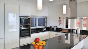 Una cocina moderna con electrodomésticos de acero inoxidable, una encimera negra y un frutero.