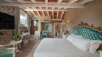 Une chambre avec un grand lit, un mur en pierre, un plafond en bois et une petite table sur laquelle est posée une plante.
