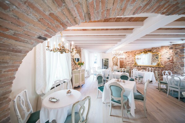A dining area with brick walls, white tables, and green chairs. - Regia Rosetta (Valeggio sul Mincio)