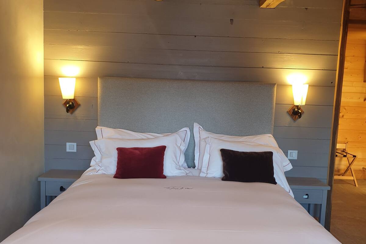A bed with a grey headboard, two bedside tables, and two wall-mounted lights.