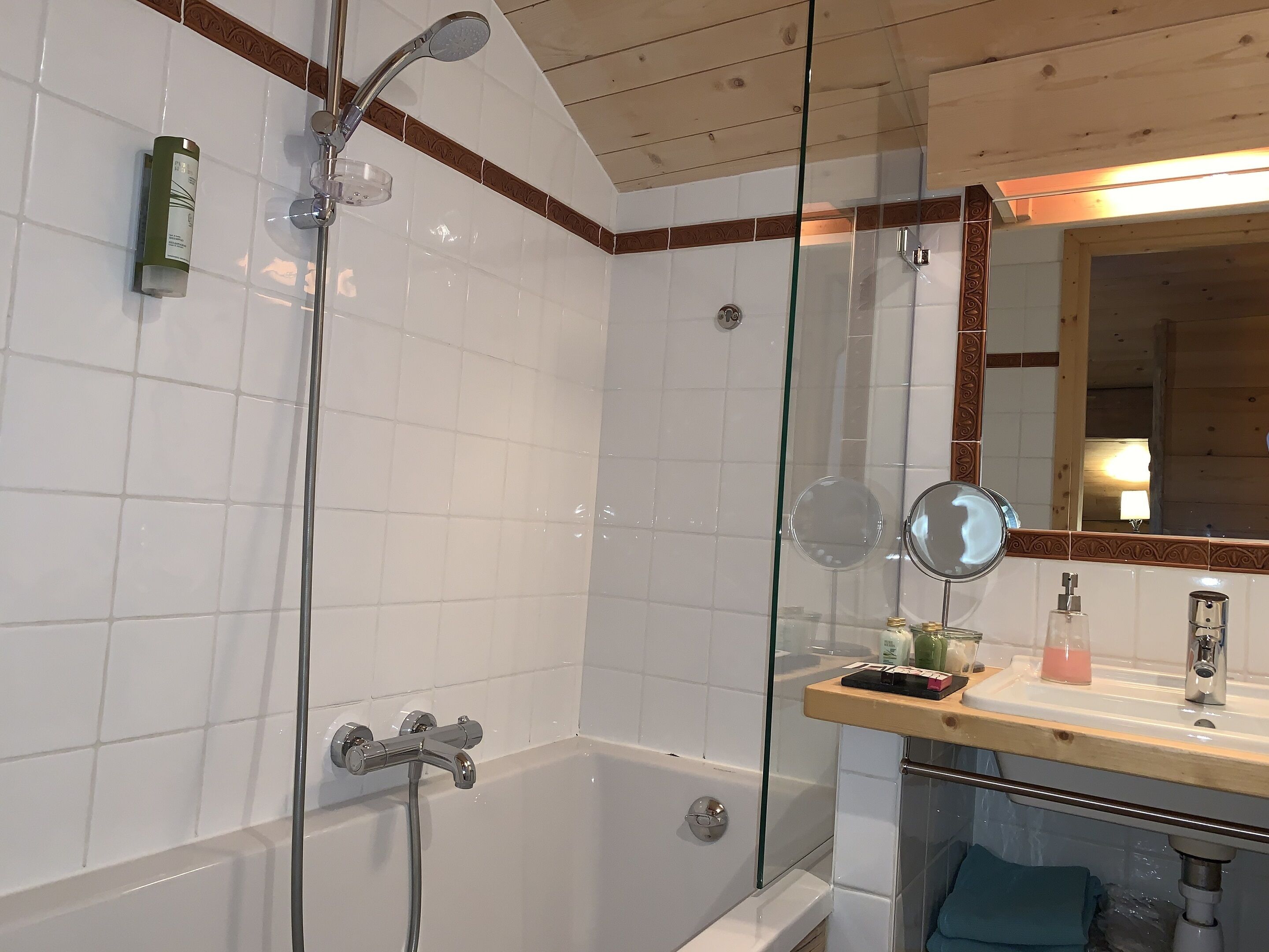 Une salle de bain moderne avec une douche à l’italienne en verre, un meuble-lavabo en bois avec un miroir et une baignoire.