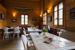 Un intérieur en bois avec des tables et des chaises, un banc et des lampes fixées au mur.