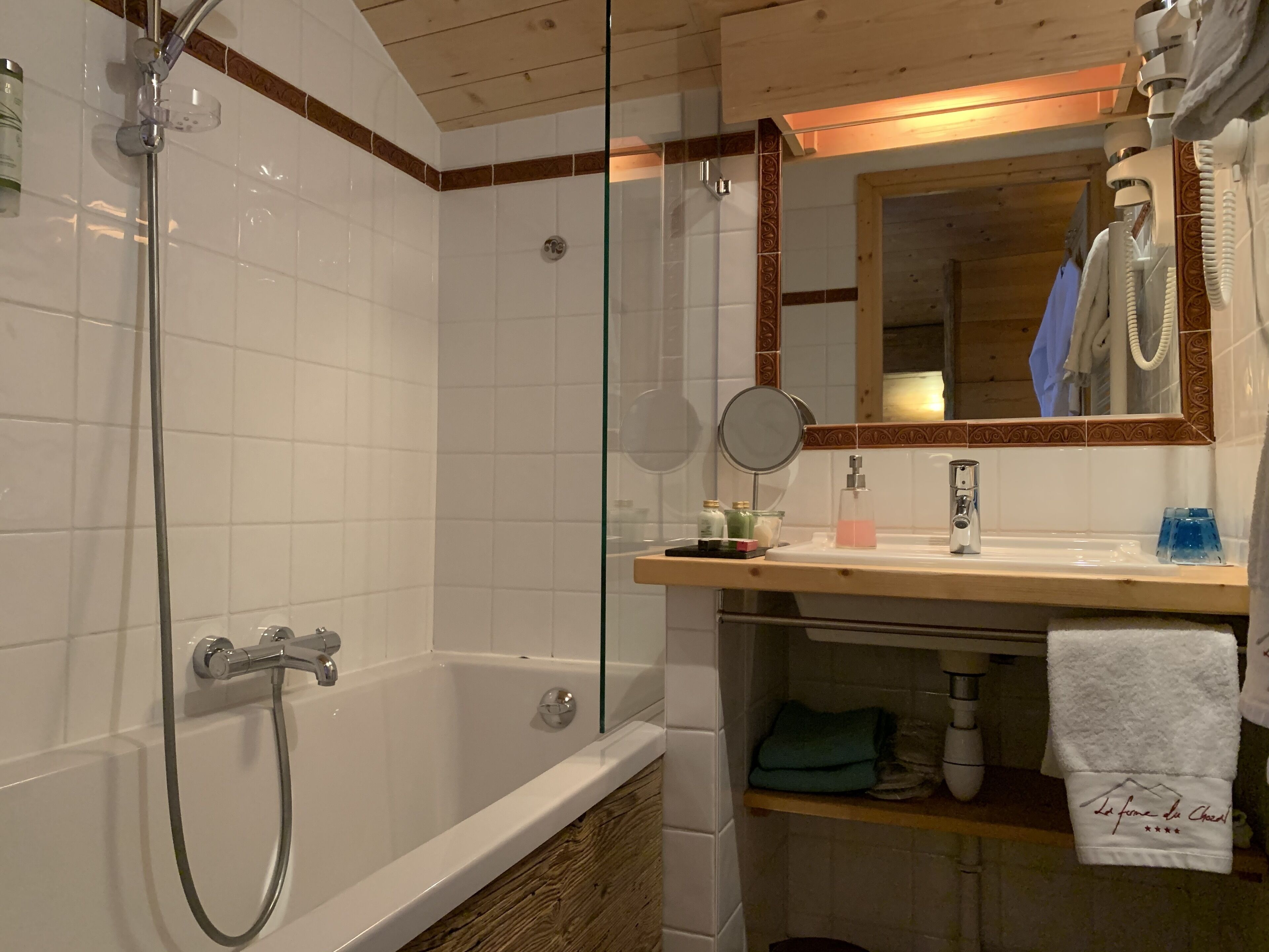 A bathroom with a glass-enclosed shower, a wooden vanity with a mirror, and a towel hanging on a rack.
