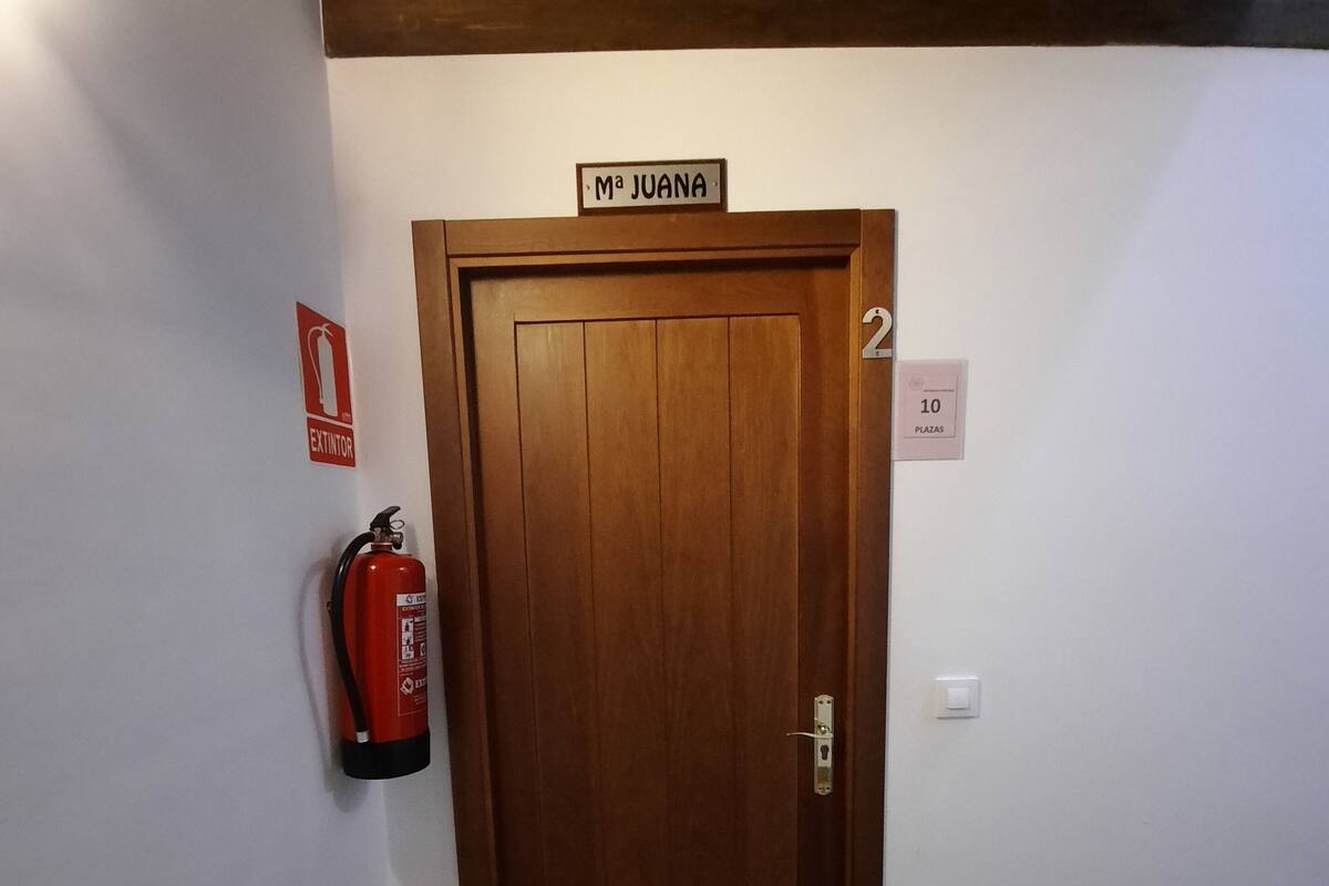 A wooden door with a sign above it, a fire extinguisher mounted on the wall, and a number sign indicating the floor level.