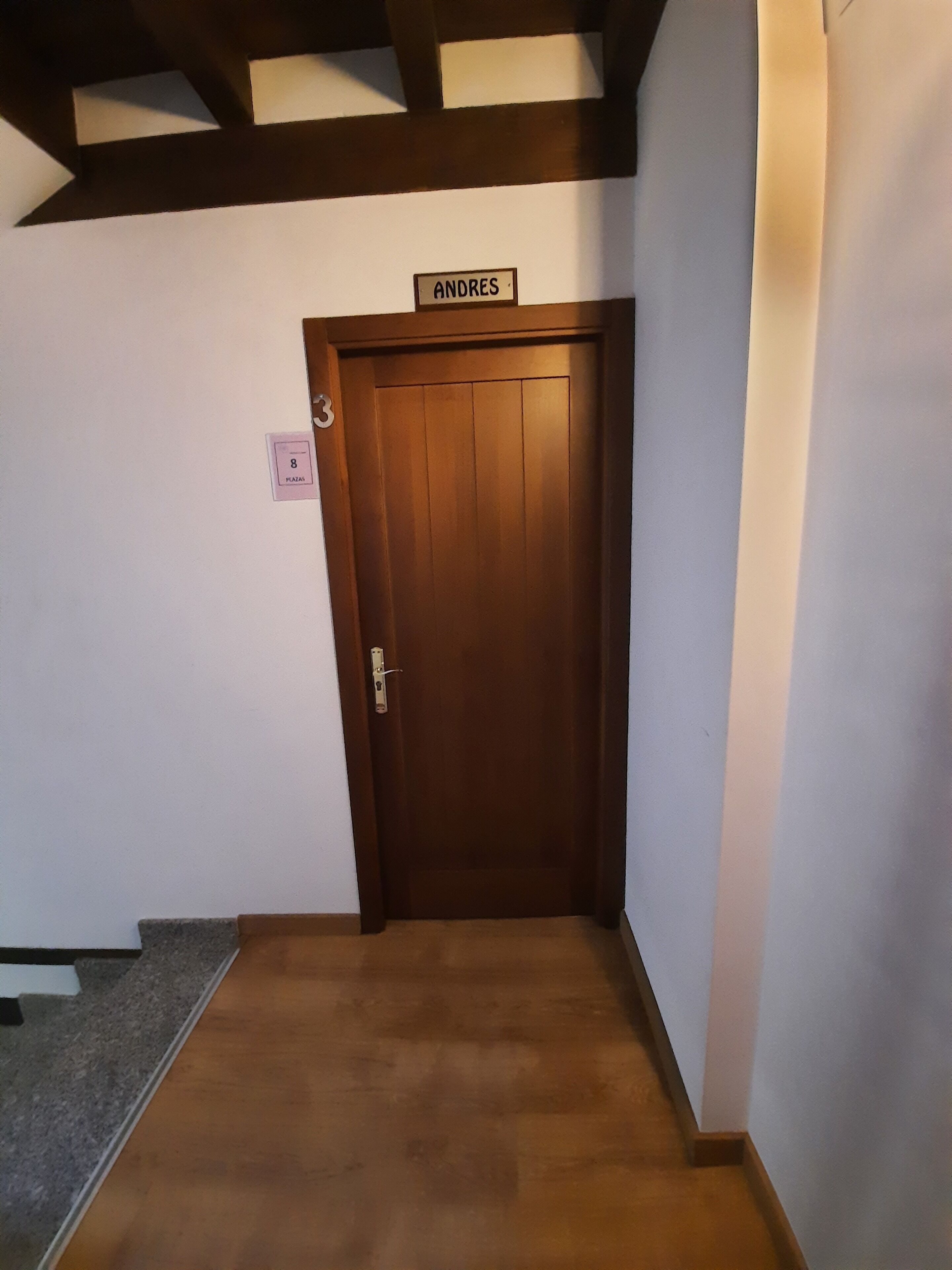 Un pasillo con una puerta de madera que lleva el nombre 'ANDRES'.