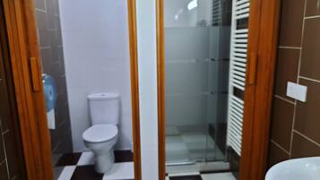 Ein Badezimmer mit Toilette, Duschbereich und Waschbecken.