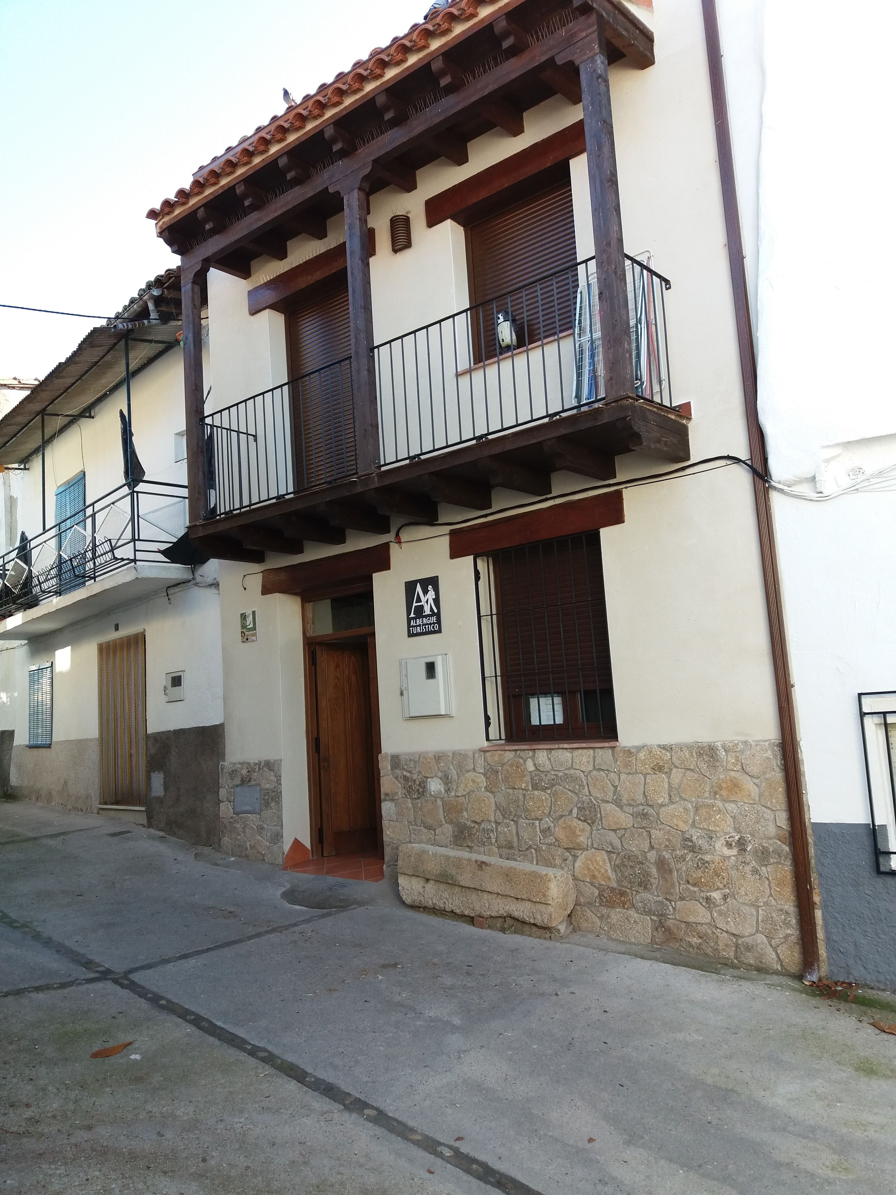Un bâtiment à deux étages doté d’un balcon, d’une base en pierre et d’une enseigne indiquant qu’il s’agit d’un hôtel pour touristes.