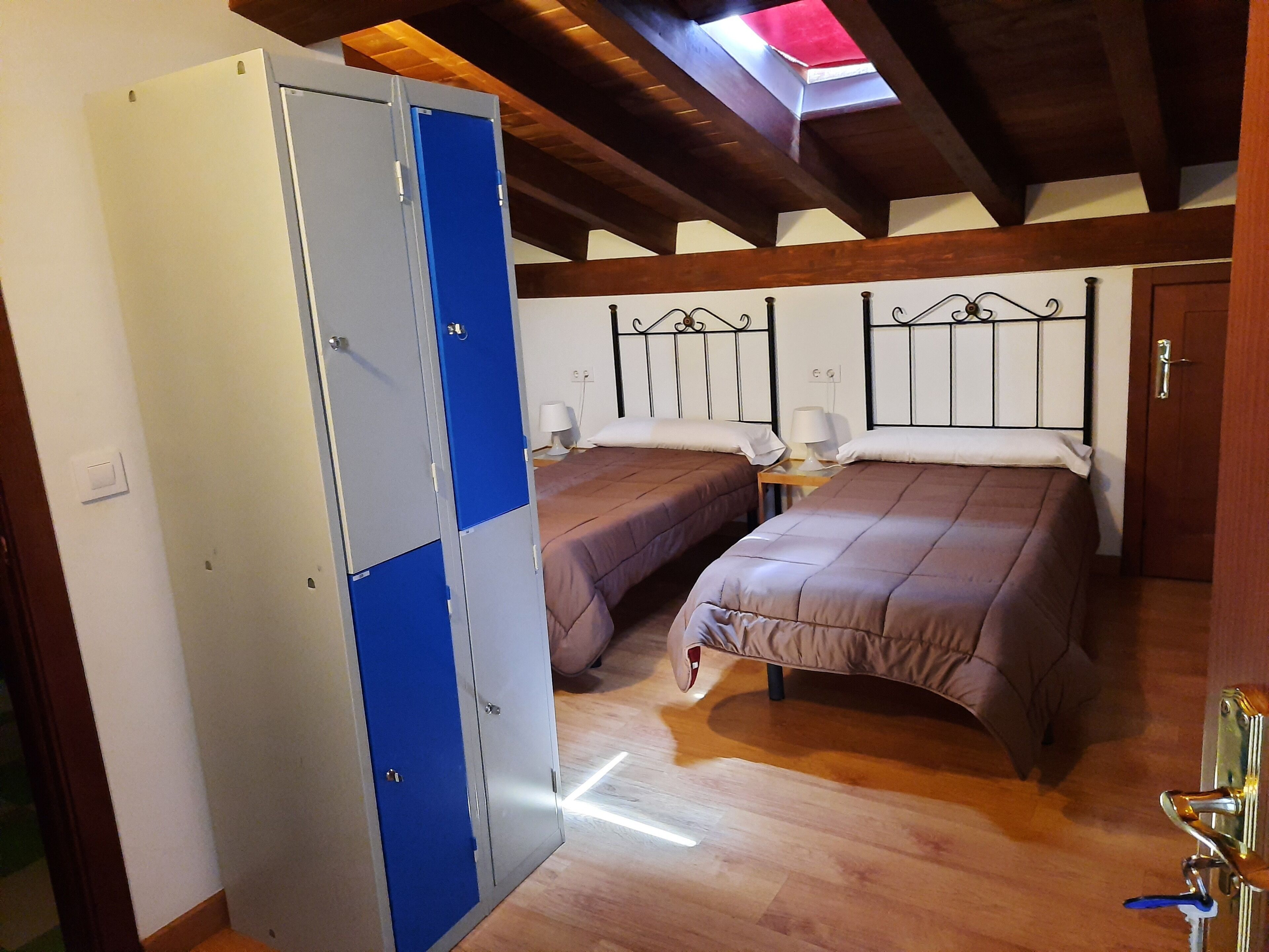 Een slaapkamer met twee bedden, een kledingkast en een dakraam.