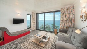 A living room with a large window, a flat-screen TV, a sofa, a coffee table, and a lamp. - Cottage do Mar by Our Madeira (Calheta)