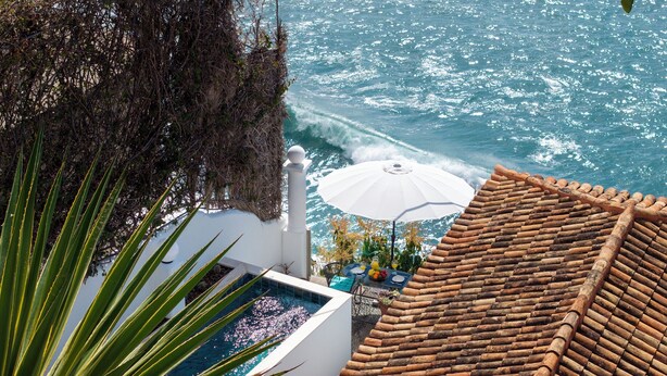 A rooftop pool with a view of the ocean, a white umbrella, and a tiled roof. - Cottage do Mar by Our Madeira (Calheta)