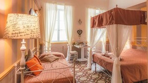 A bedroom with two beds, a bedside table, a lamp, and a window with curtains. - Ghibellino B&B (Arezzo)