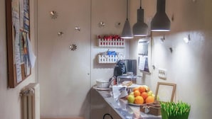 A kitchen with a long counter, pendant lights, a radiator, and a small table with fruits and a picture frame. - Ghibellino B&B (Arezzo)