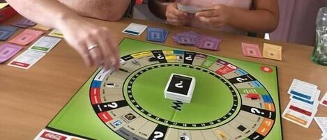 Two people playing a board game at a table with a game board, cards, and tokens.