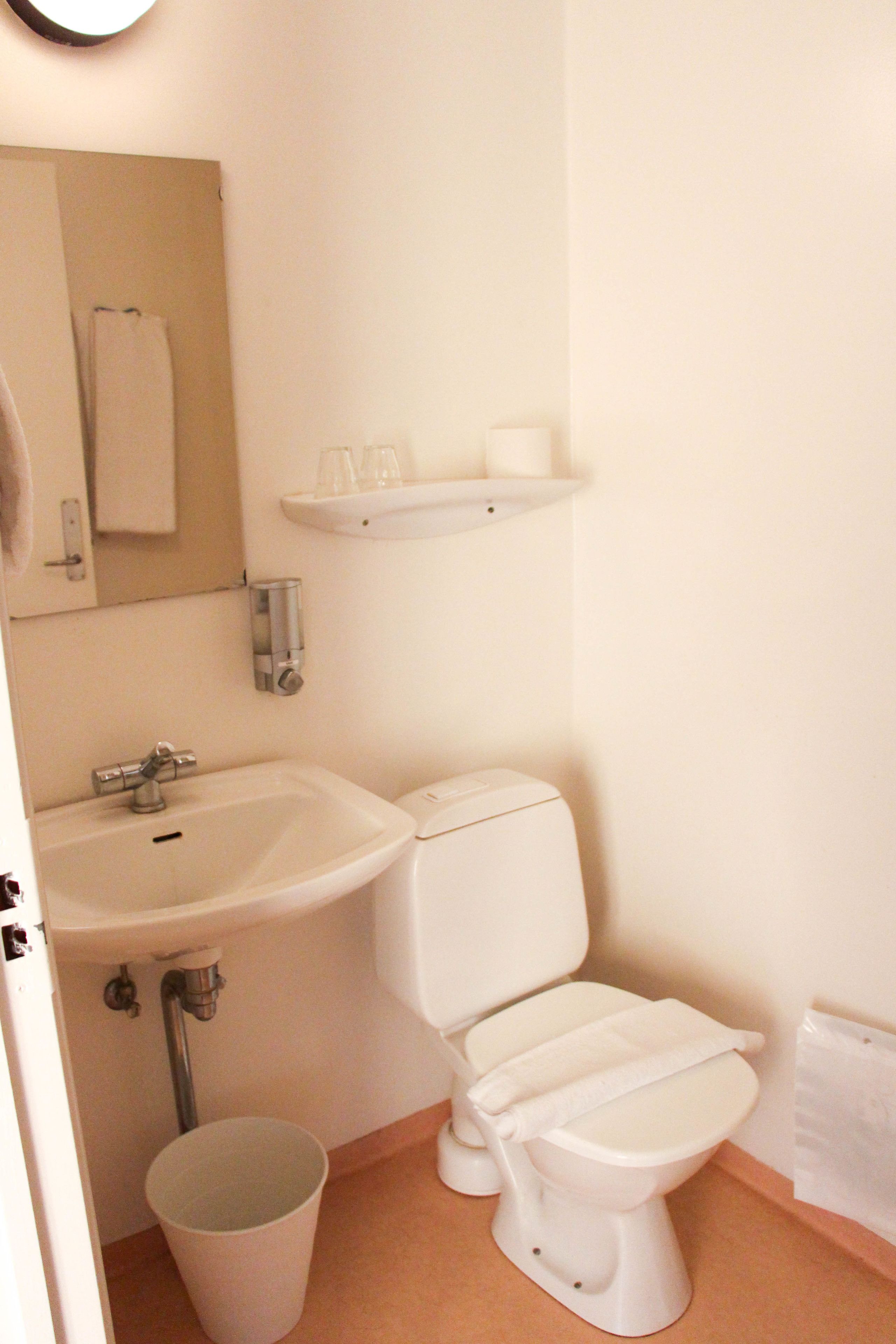Un baño con lavamanos, inodoro y un cubo de basura.