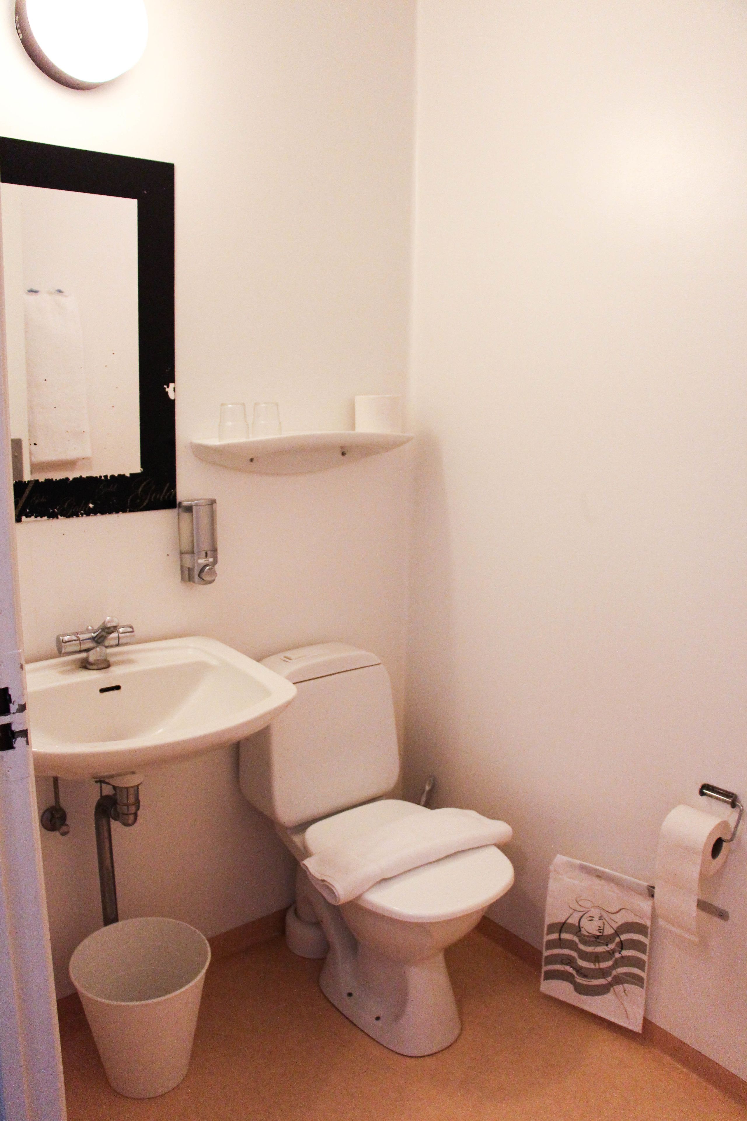 A small, clean bathroom with a sink, toilet, and a mirror.