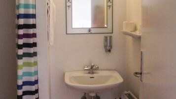 Un baño con cortina de ducha a rayas, un lavabo, un espejo y un radiador.